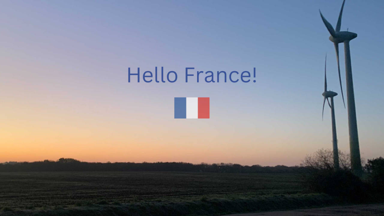 This is an image of a wind turbine with a French flag in the middle of the image with the text 'Hello France!' above it.