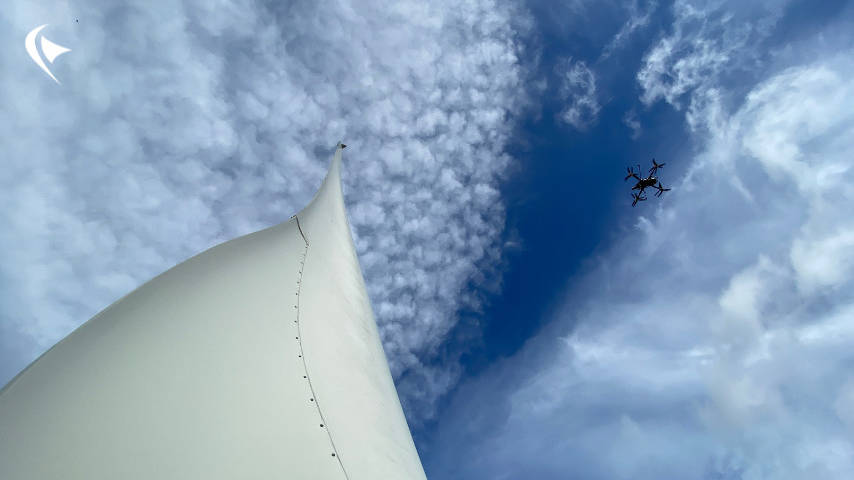 This is an image of a wind turbine blade with Perceptual Robotic's drone inspecting the blade.