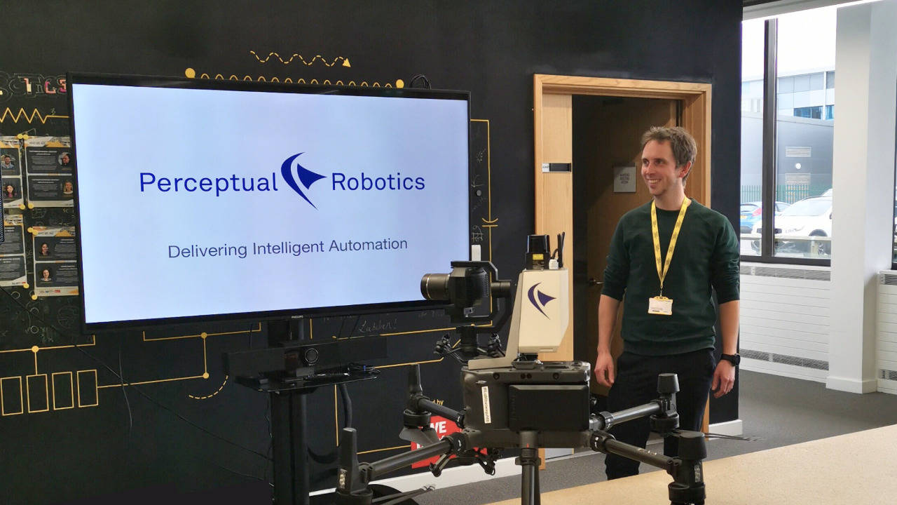 Chris standing with drone and Perceptual Robotics presentation 