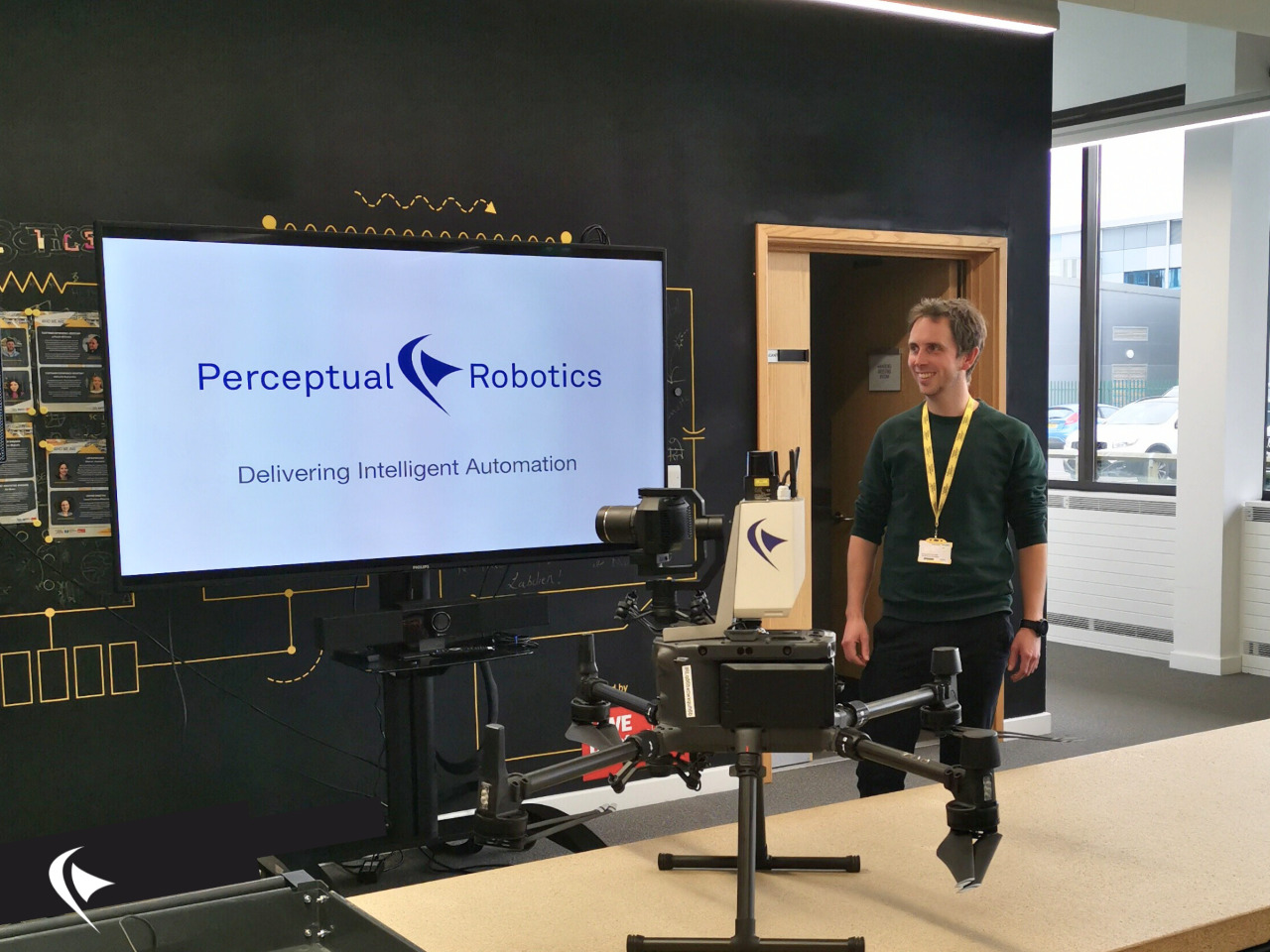 Chris standing with drone and Perceptual Robotics presentation